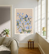 July birth flower art print of blue larkspur on sand in a gold frame, July Larkspur lettering, leaning against a panelled wall