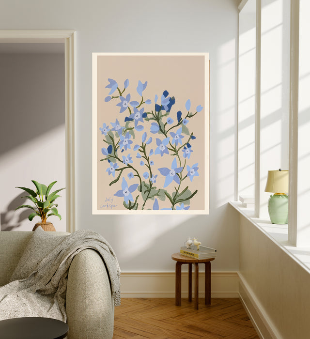 July birth flower art print of blue larkspur on sand in a gold frame, July Larkspur lettering, leaning against a panelled wall