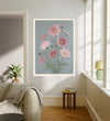 Cosmos October birth flower print hanging in a sunlit living room above a linen armchair with side table and plant