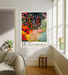 Japanese exhibition poster of a wildflower meadow hanging in a sunlit living room above a linen sofa with side table