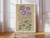 Aster September birth flower print hanging in a sunlit living room above a linen armchair with side table and plant