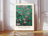 Van Gogh Almond Blossom art print in emerald green with pink blossoms, cream border, displayed above a rattan basket in a neutral bedroom