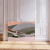 Snowy cabin winter landscape print, glowing cabin beneath pink sky and golden moon with rolling grey hills, leaning against a panelled wall