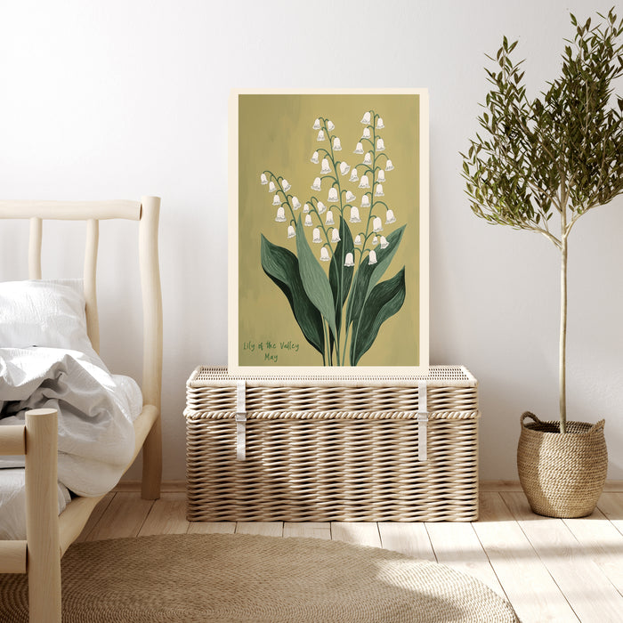 Lily of the valley birth month flower print resting on a wicker chest beside a bed and olive tree in a neutral bedroom