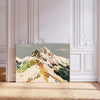 Colourful abstract snowy mountain art print with green, yellow, red and pink brushstrokes on a grey sky, landscape format, leaning against a white panelled wall
