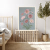 Cosmos botanical birth flower print resting on a wicker chest beside a bed and olive tree in a neutral bedroom