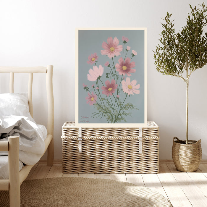 Cosmos botanical birth flower print resting on a wicker chest beside a bed and olive tree in a neutral bedroom