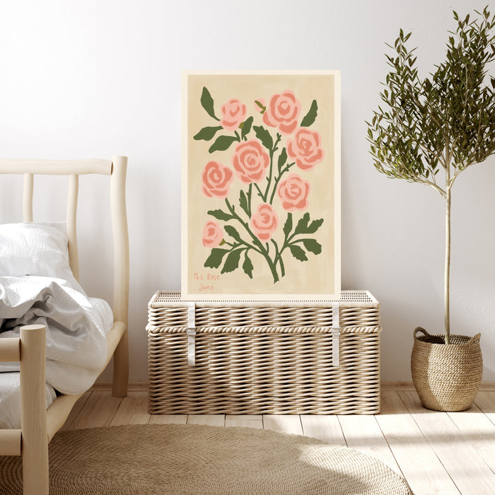 Pink rose birth month flower print resting on a wicker chest beside a bed and olive tree in a neutral bedroom