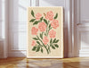 The Rose June birth flower print hanging in a sunlit living room above a linen armchair with side table and plant