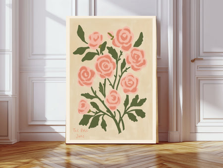 The Rose June birth flower print hanging in a sunlit living room above a linen armchair with side table and plant