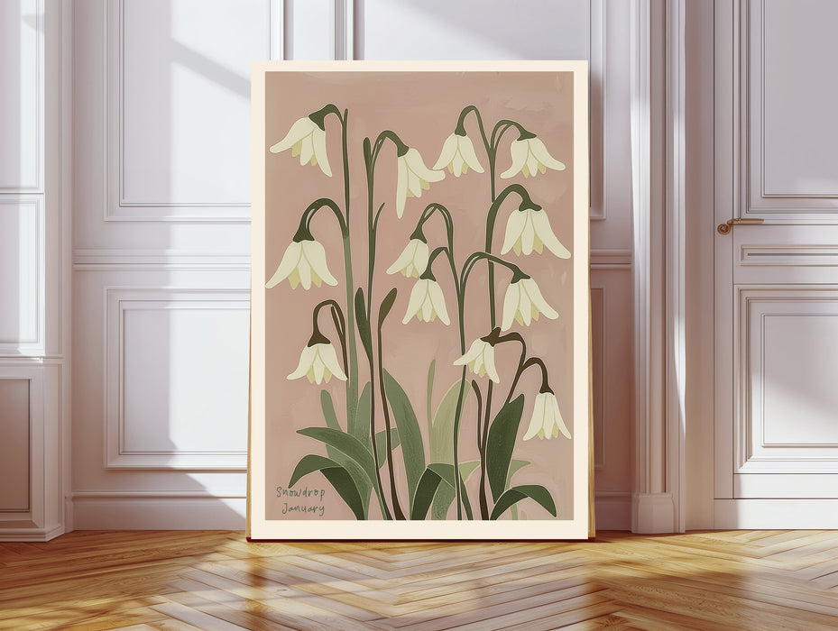 January birth flower art print of white snowdrops on dusty pink in a gold frame, Snowdrop January lettering, leaning against a panelled wall