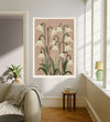 White snowdrop botanical art print hanging in a sunlit living room above a linen armchair with side table and plant